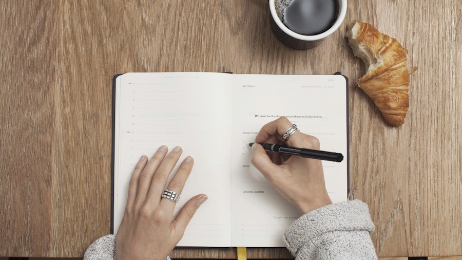 Hands writing in a notebook on a study desk