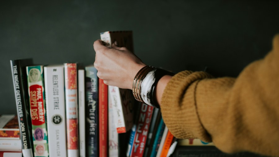 A person selecting a book from a shelf