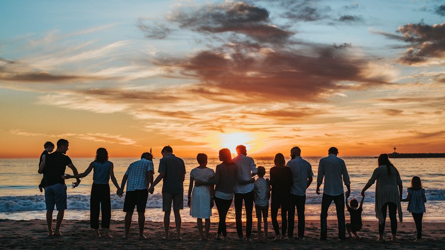 A group gathered along the beach at sunset