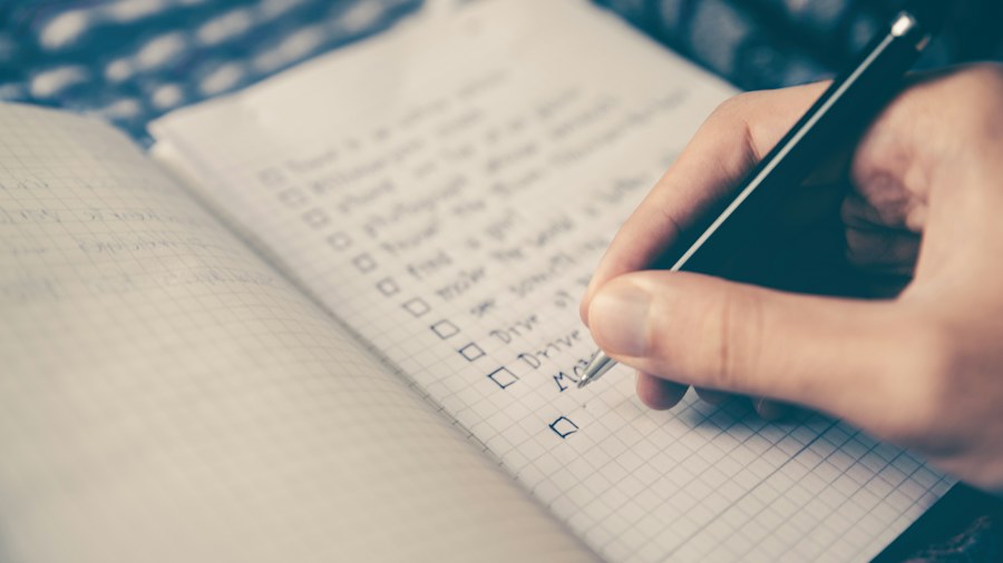 A person organizing tasks in a written checklist