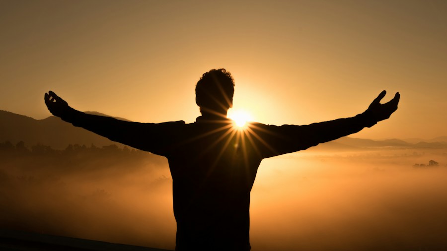 A person stretching their arms toward the sunlight